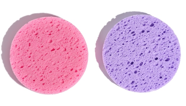 Esponjas de maquillaje redondas de color púrpura y rosa sobre un fondo blanco aislado