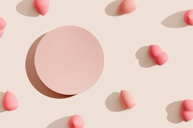 Esponjas de maquillaje rosa alrededor de la plataforma redonda sobre sombra beige a la luz del sol Fondo cosmético para produc