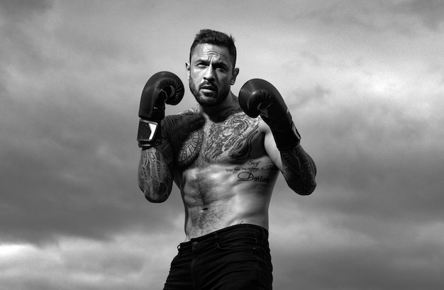 Esporte boxeador atleta boxeador lutando no céu fundo homem atlético forte com luvas de boxe
