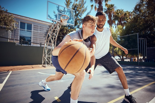 Esporte de basquete e fitness com amigos em uma quadra de esportes ao ar livre com um oponente para um jogo ou partida Treinamento de exercícios e treino com um atleta do sexo masculino e sua competição pela saúde