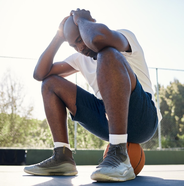 Esporte de depressão e homem na quadra de basquete para fitness ao ar livre Saúde mental de atleta negro estressado e cansado após treino de bem-estar ou esgotamento de treinamento de exercícios em parque esportivo com bola