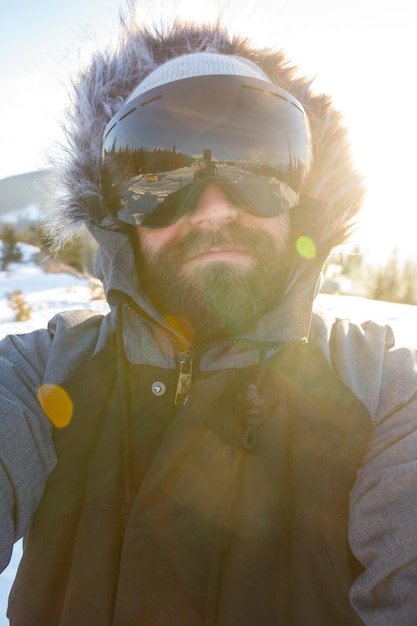 Esporte de inverno e conceito de pessoas snowboarder freerider em pé na encosta íngreme do pico da montanha e tirando selfie retrato com câmera ou smartphone no fundo das montanhas nevadas na estância de esqui