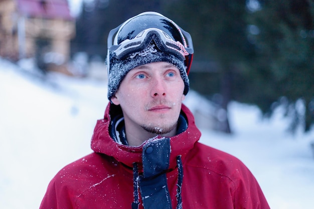 Esporte de lazer de inverno e conceito de pessoas Snowboard de homem nas montanhas Snowboarder descansando no topo da montanha em um fundo de céu azul Estância de esqui