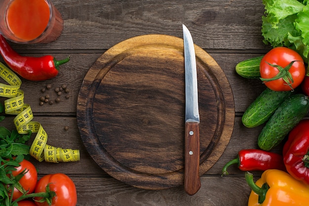 Esporte e dieta. Legumes, um copo de suco de tomate e centímetro. Pimentas, tomates, salada em fundo rústico. Vista do topo. Copie o espaço