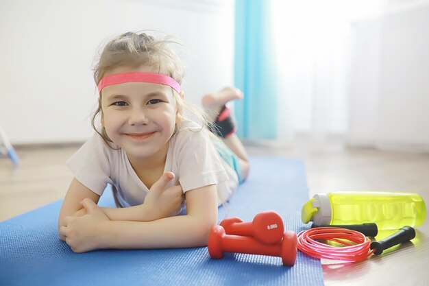 Esporte e estilo de vida saudável. criança praticando esportes em casa. haltere de tapete de ioga e corda de pular. currículo desportivo com conceito de exercícios em casa.