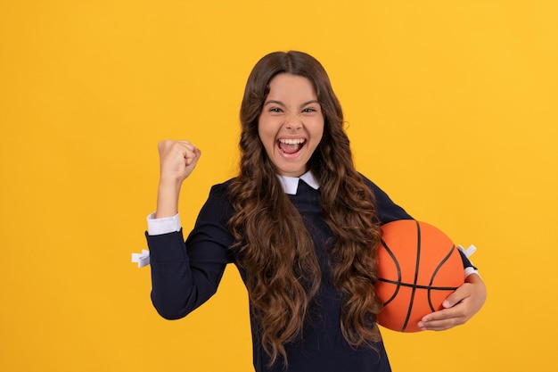 Esporte e passatempo. atividade de verão. menina adolescente com bola de basquete. jogador de basquete infantil. escola de esporte. criança feliz na aula de treinamento físico. de volta à escola. comemorando o sucesso.