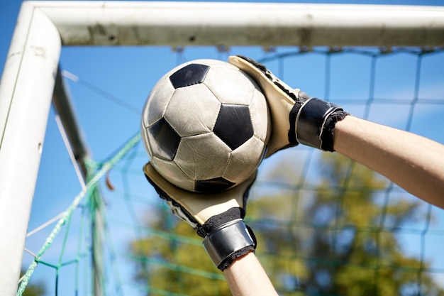 esporte e pessoas - jogador de futebol ou goleiro pegando bola no gol de futebol em campo