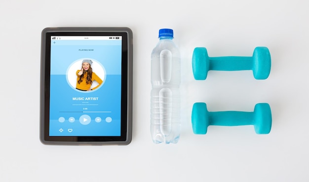 Foto esporte, estilo de vida saudável, fitness, tecnologia e conceito de objetos - close-up do computador tablet pc com halteres e garrafa de água sobre fundo branco