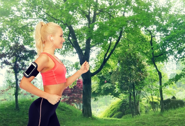 esporte, exercício, tecnologia, internet e saúde - mulher desportiva sorridente correndo e ouvindo música do smartphone