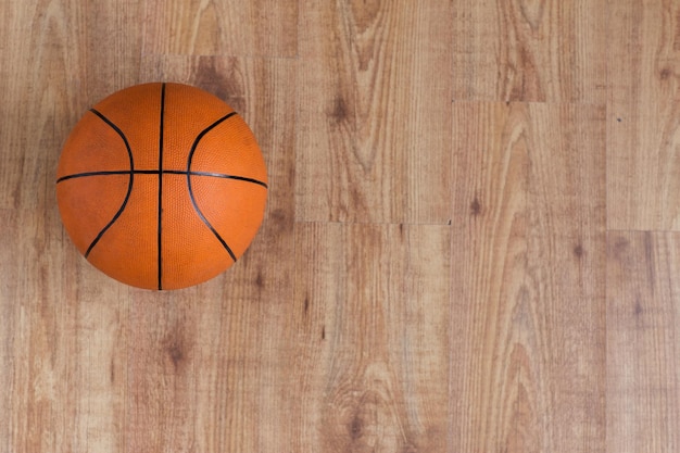 esporte, fitness, jogo, equipamentos esportivos e conceito de objetos - close-up da bola de basquete no chão de madeira de cima