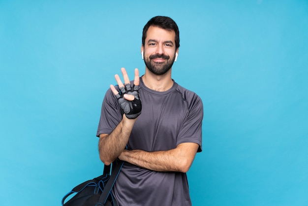 Esporte jovem homem com barba sobre azul isolado feliz e contando quatro com os dedos