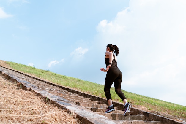 Esporte jovem mulher correndo ao ar livre no andar de cima no céu azul