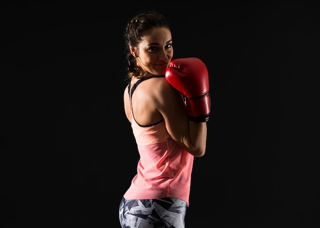 Esporte mulher em fundo escuro com luvas de boxe