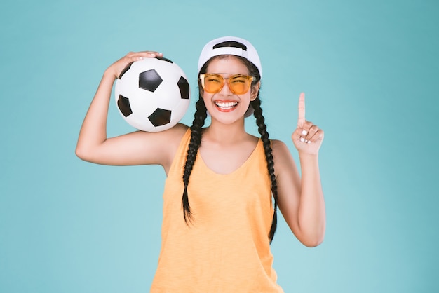 esporte, mulher, ventilador, segurando, um, bola futebol, celebrando, apontar um dedo, cima, vencedor, sinal