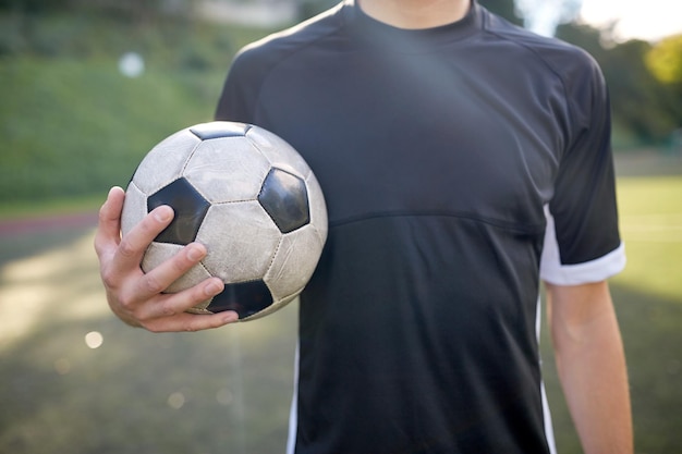 esporte, treinamento de futebol e pessoas - close-up de jogador de futebol com bola no campo