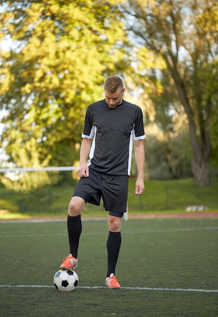 esporte, treinamento de futebol e pessoas - jogador de futebol jogando com bola no campo