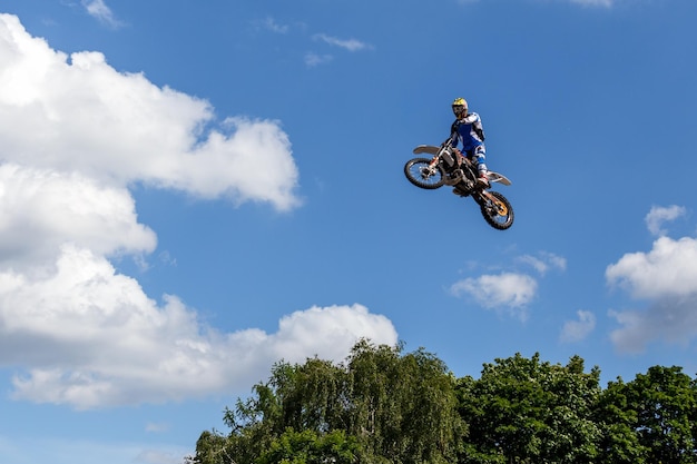 Esportes adrenalina de velocidade extrema motociclista pulando em sua motocicleta e voando no céu entre nuvens