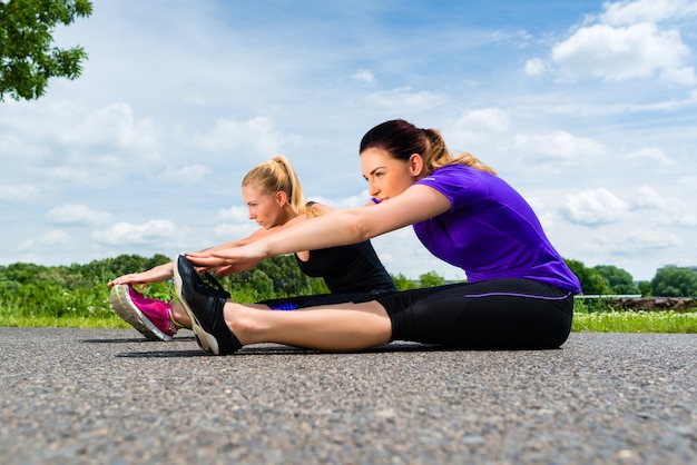 Esportes ao ar livre - mulheres jovens fazendo fitness no parque