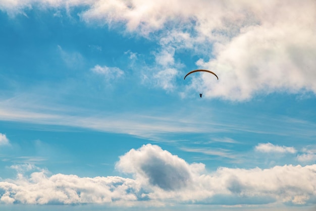 Esportes ativos de parapente com pára-quedas voando contra montanhas com florestas exuberantes nas terras altas iluminadas pela luz do sol sob céu nublado