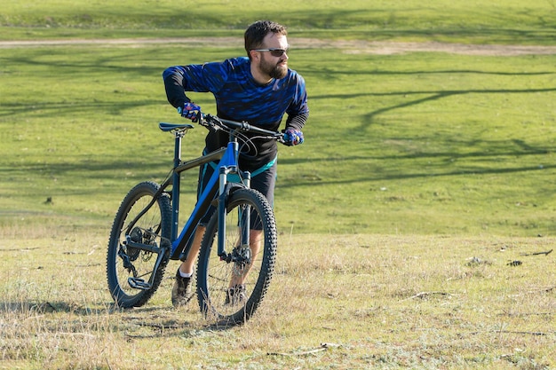 Esportes brutal barbudo em uma mountain bike moderna Um ciclista em um lugar deserto de sal à beira do lago