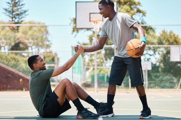 Esportes de basquete e trabalho em equipe ajudando e apoiando respeito e assistência em jogos de treinamento de competição feliz jogador de basquete de mãos dadas com amigo confiança e bondade na quadra ao ar livre