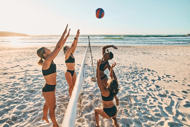 Esportes de equipe de vôlei e mulheres na praia durante férias em grupo juntos em Miami no verão Felizes amigos animados e jovens jogando esporte em biquíni à beira-mar de férias com energia