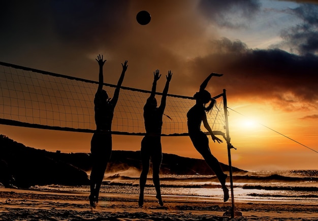 Esportes de praia e vôlei ao pôr do sol por silhueta de mulheres pulando para bola juntos viagens divertidas e verão Energia fitness e exercícios com amigos de esportes jogando vôlei de praia no Brasil