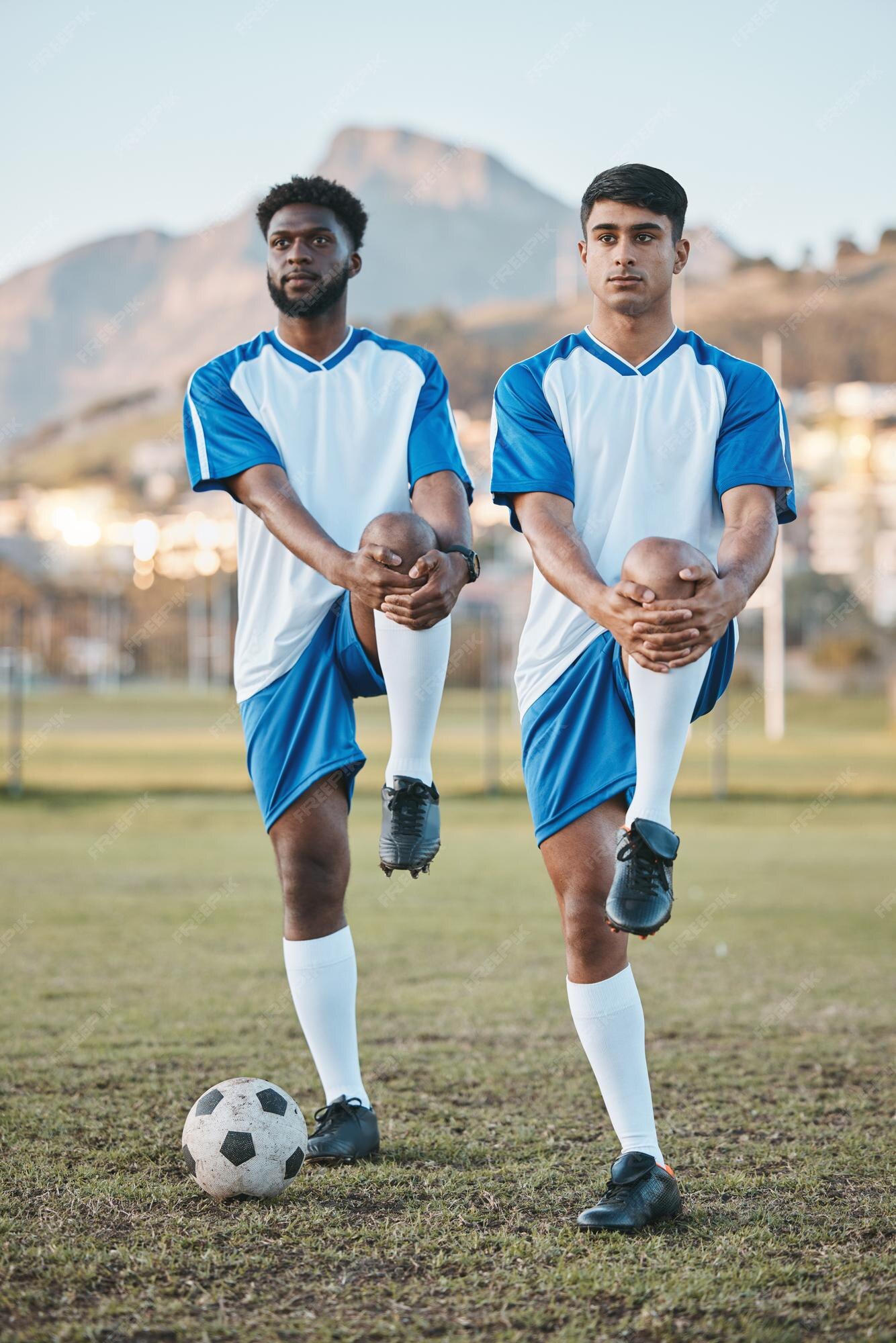 Dois jogadores de futebol fazendo exercícios de alongamento no campo.  treinamento de futebol em estádio ao ar livre, treino em equipe antes do  jogo