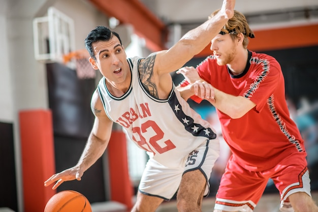 Esportes. Dois jovens jogando basquete e animados