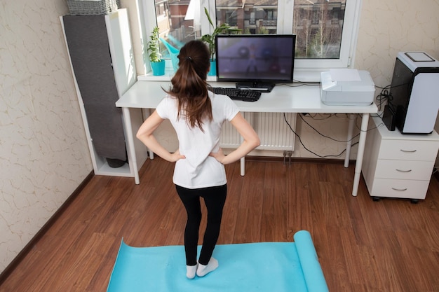 Esportes durante a quarentena Jovem fazendo exercícios olhando para o monitor