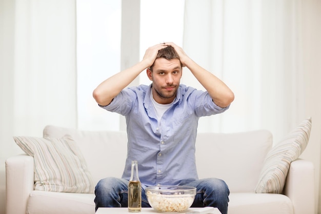 esportes, felicidade e conceito de pessoas - homem triste assistindo esportes na tv e equipe de apoio em casa