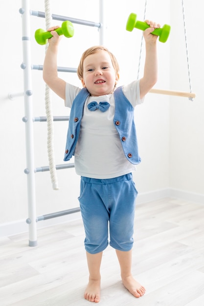 Esportes para bebês em casa, menino bonito levanta halteres, o conceito de esportes e saúde infantil