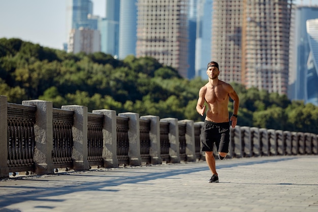 Esportes urbanos Homem esportivo sem camisa correndo para fitness no parque da cidade em um lindo dia de verão