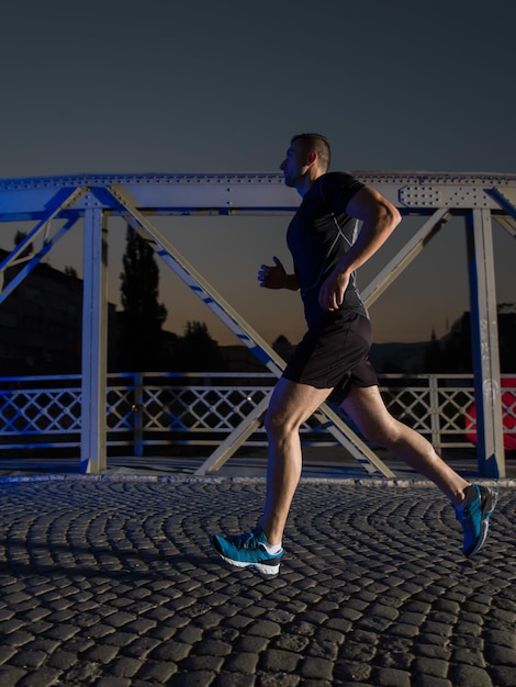 esportes urbanos, jovem saudável correndo pela ponte da cidade no início da manhã à noite