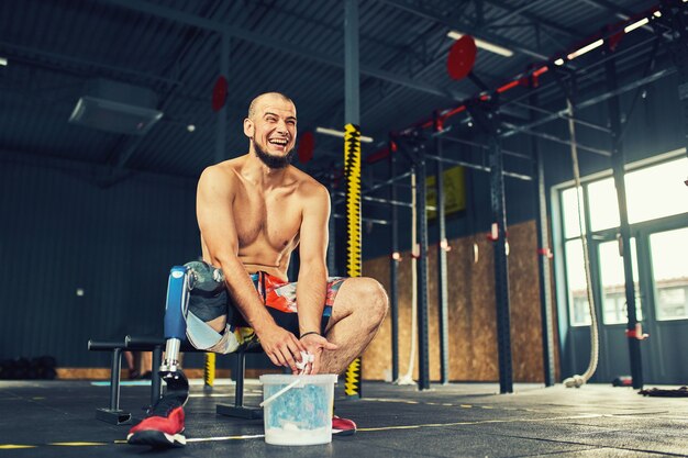 Foto esportista com prótese malhando na academia