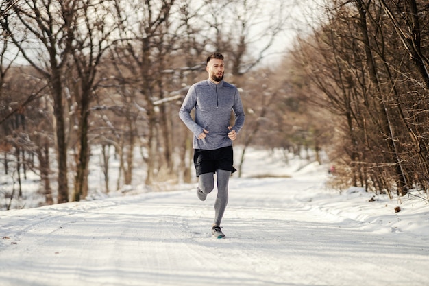 Esportista correndo no caminho de neve na natureza, fitness de inverno, fitness ao ar livre, vida saudável.