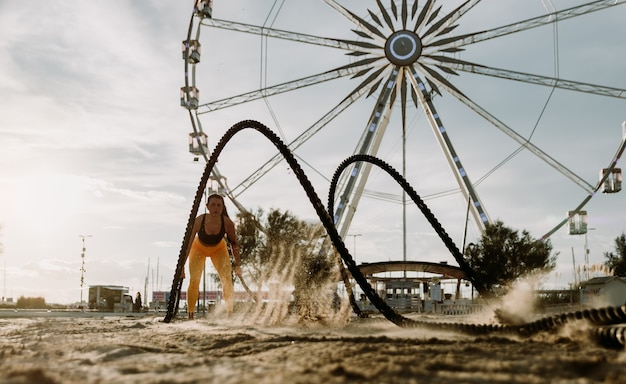 Esportista em forma e tonificada malhando em uma academia de treinamento funcional na praia