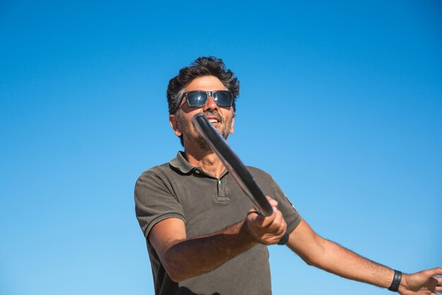 Esportista jogando tênis na praia com fundo de céu azul. Jogador de Paddle