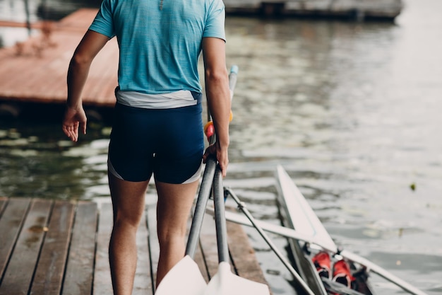 Esportista, remador com um único scull homem, prepara-se para a competição com barco