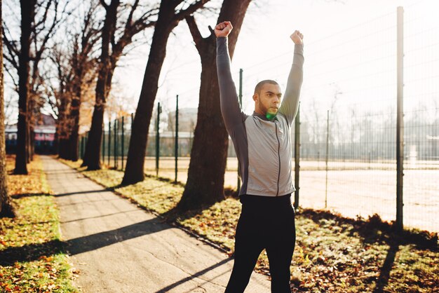 Esportista se aquecendo antes de correr no parque de outono