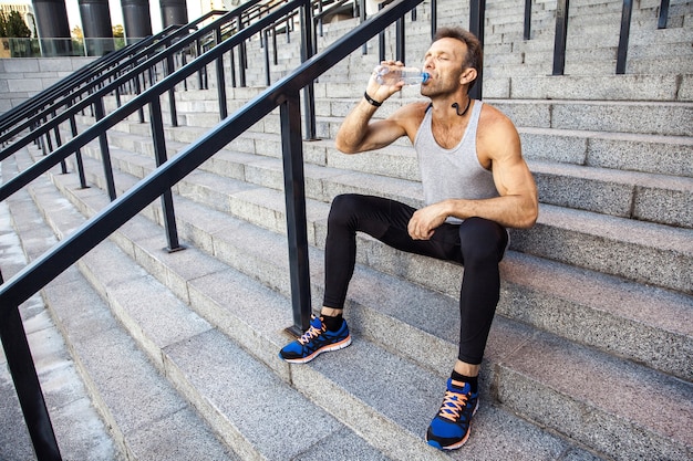 Esportista sedento descansar e beber água após a corrida. fitness, esporte, exercício e conceito de estilo de vida saudável de pessoas.