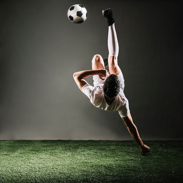 Esportista sem rosto caindo e chutando a bola