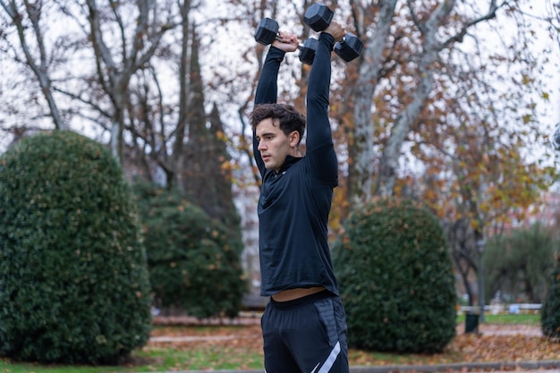 Esportista treinando com halteres no parque