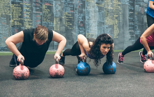 Foto esportistas fazendo flexões com kettlebells