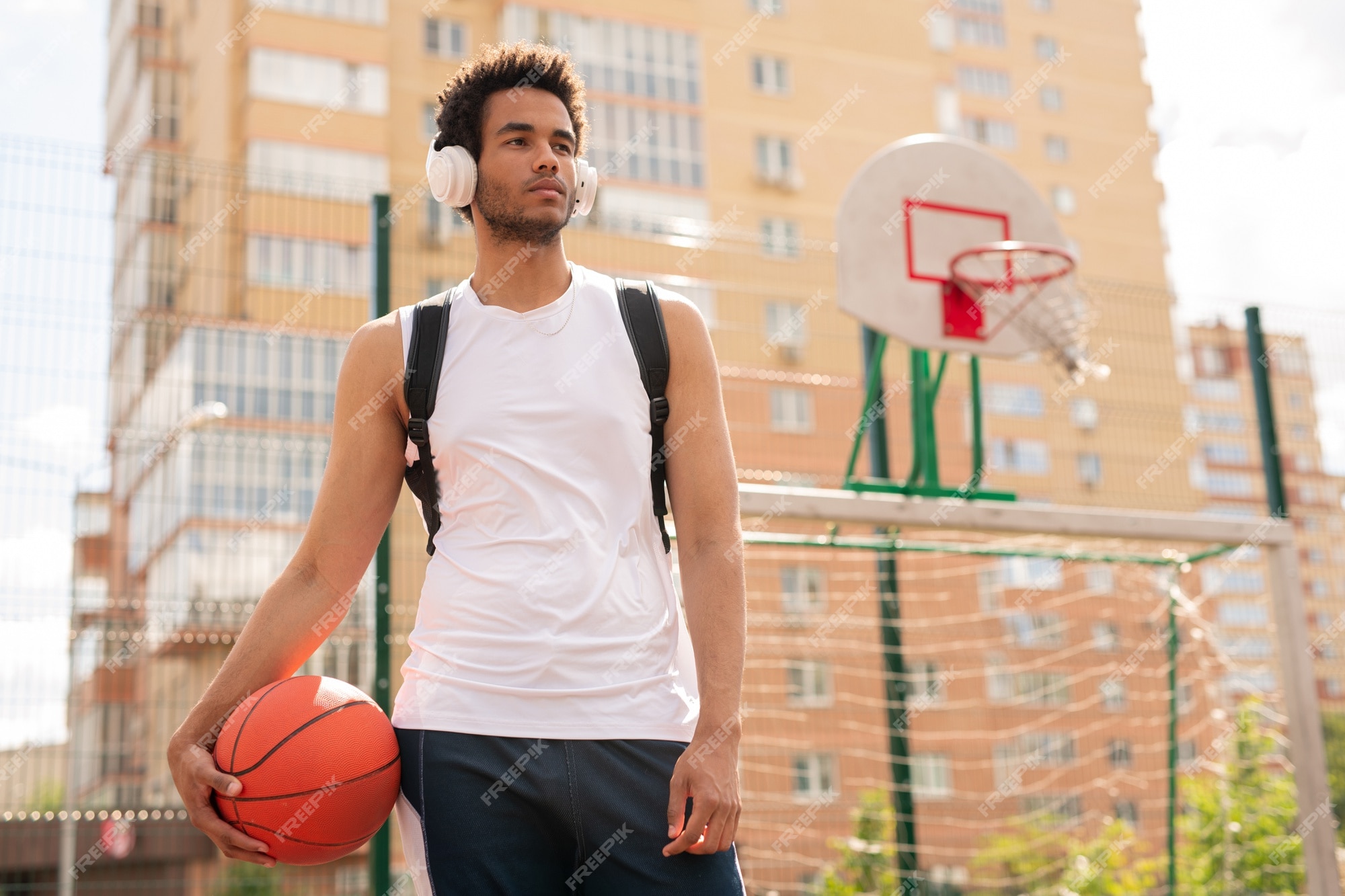 Esportivo com bola para jogar basquete, ouvindo música em fones