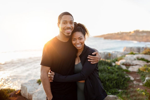 Esposa afro-americana positiva do milênio abraça marido em roupas esportivas e desfruta de cuidados corporais ativos juntos