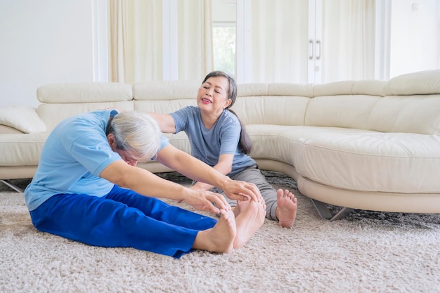 Esposa anciana ayudando a marido mayor a hacer estiramientos