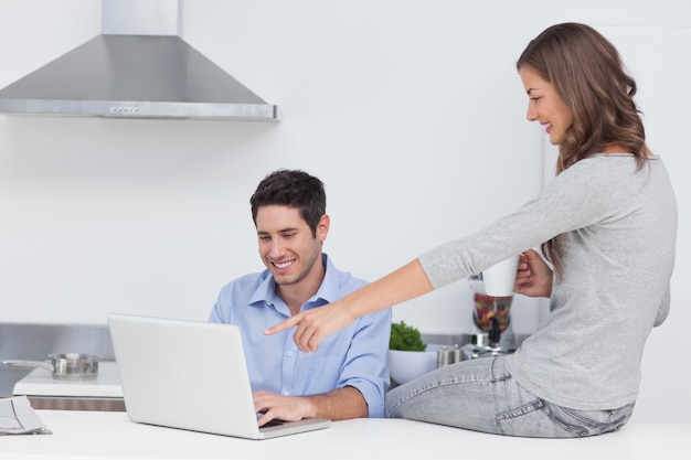 Esposa apuntando a la computadora portátil de su marido