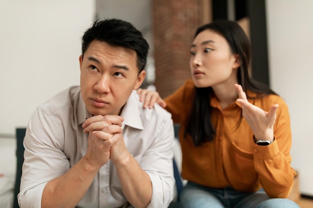 Esposa chinesa emocional gritando e gesticulando para o marido de meia-idade tendo dificuldades no casamento