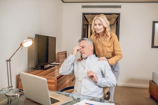 Foto esposa cuidadosa. un hombre que trabaja desde casa y se siente cansado, su esposa lo apoya